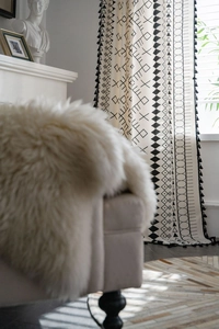 Detail of bohemian cotton linen curtain with black geometric patterns and fringe tassels