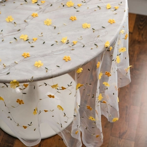 Elegant white mesh tablecloth with yellow floral embroidery on a marble dining table