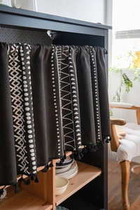 Detail of black geometric pattern curtain with fringe tassels for kitchen cabinets