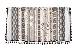 Détail du rideau à motif géométrique boho avec pompons noirs et texture en lin