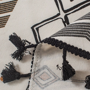 Détail d'un rideau tissé avec motif de flèches et bordures à pompons noirs élégants