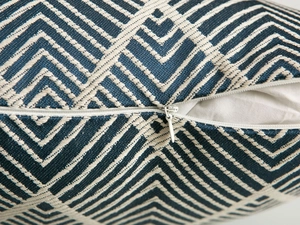 Detail of the hidden zipper and geometric woven fabric texture on a blue cushion cover