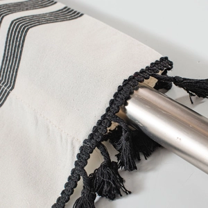Détail du rideau en lin beige avec rayures géométriques et pompons noirs élégants