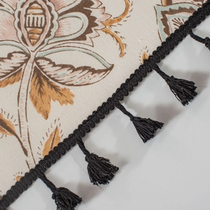 Detailed macro view of vintage floral print fabric with premium black tassel fringe trim