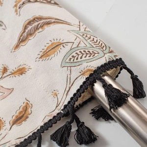 Detail of floral printed cafe curtain with rustic leaf patterns and black tassel fringe