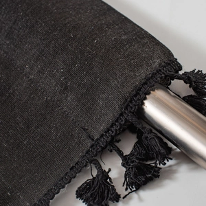 Detail of black geometric print fabric with dense tassels on a metal hanging rod