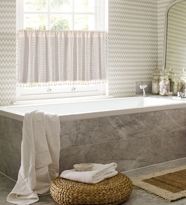 Close-up of white crochet lace cafe curtain with geometric patterns and fringe tassels
