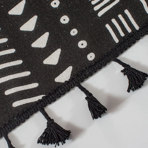 Close-up of bohemian geometric patterns with black woven fringe and tassel details