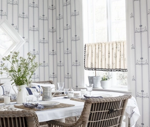 Detail of floral print cafe curtain with black tassels in a Nordic style kitchen setting