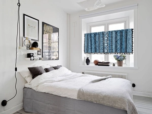 Close-up of blue Bohemian cafe curtain with geometric prints and black tassel fringe