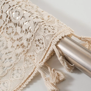 Macro detail of cream lace valance with hollow crochet patterns and woven tassels