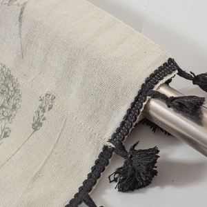Detail of floral printed linen curtain with black woven lace trim and decorative tassels