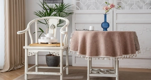 Detail of round dusty pink tablecloth with cotton linen texture and cream fringe edges