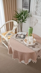 Detailed view of beige tassel fringe and geometric jacquard pattern on round tablecloth