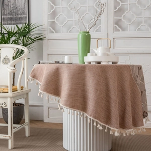 Detail of vintage coffee-colored linen tablecloth featuring white tassels and geometric patterns
