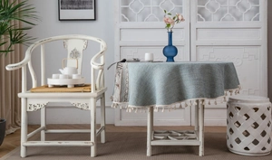 Detail of round gray-blue tablecloth with fringe trim and retro pattern in home setting