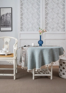 Detail of round linen texture tablecloth with teal pattern borders and cream fringe tassels