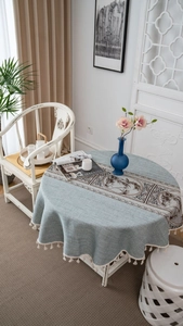 Detailed close-up of light blue round tablecloth with tassels and Chinese ink painting