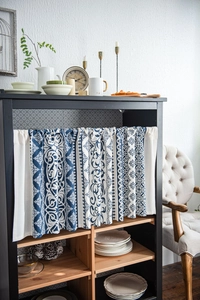 Detailed view of blue floral cabinet curtain with elegant scroll patterns in a kitchen