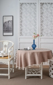 Close-up of round jacquard tablecloth with rustic linen texture and white fringe tassels