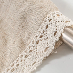 Detailaufnahme von Leinenvorhang mit eleganter weißer Spitzenborte an Metallstange
