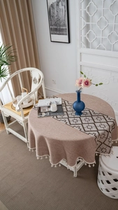 Detail of round jacquard tablecloth with geometric pattern and white cotton tassels