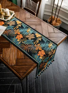 Dettaglio del runner da tavolo stile giungla tropicale con stampa leopardo e nappe verdi