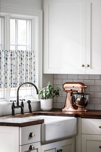 Detail of blue striped linen cafe curtain with beige tassels in a modern kitchen setting