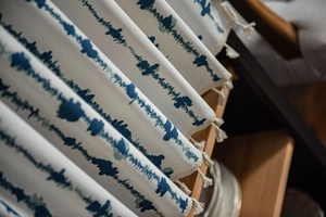 Close-up of blue striped printed fabric with elegant tassels on a wooden surface