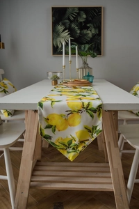 Detail of yellow lemon print table runner with pointed ends and matching cushions