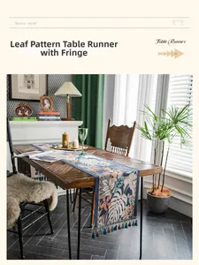 Dettaglio del runner da tavola jacquard con foglie tropicali e nappa su tavolo in legno vintage