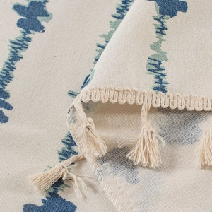 Detail of blue striped print fabric with decorative beige fringe and tassel edges
