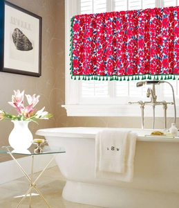 Detail of red floral cafe curtain with green tassels in a cozy bathroom setting