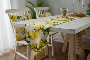 Detailed view of yellow lemon print table runner and matching cushion covers on dining table