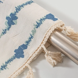 Close-up of blue wave print fabric with beige tassel fringe on a metal rod