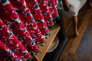 Detail of red and blue floral fabric curtain with green tassel fringe and soft texture