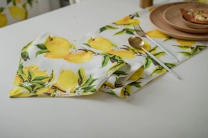 Detail of yellow lemon print table runner with textured fabric and elegant tableware