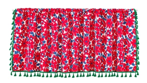 Detail of red floral curtain valance featuring dense green fringe tassels on white background
