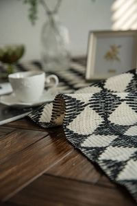 Detailed close-up of woven table runner featuring black and white diamond geometric patterns