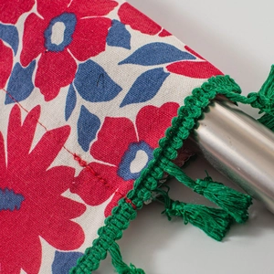 Detail of floral kitchen curtain with red and blue flowers and green fringe trim