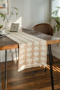 Detailed view of bohemian table runner with woven diamond patterns and elegant fringe