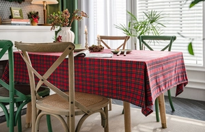 Close-up of red plaid tablecloth with rustic wooden chairs and festive decor settings