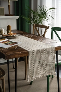 Detail of crochet boho table runner with tassels and hollow geometric pattern