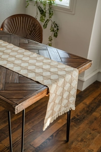 Detail of woven table runner with beige and khaki diamond pattern and fringe tassels