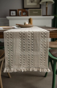 Close-up of cream woven table runner with hollow stripes and handmade tassels detail