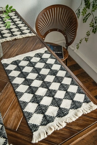 Detailed close-up of a woven cotton table runner with black and white diamond patterns