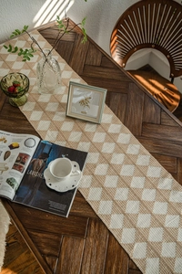 Detail of hand-woven cotton table runner featuring beige diamond patterns and texture