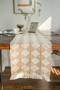 Detailed close-up of woven geometric diamond pattern and delicate fringe on table runner