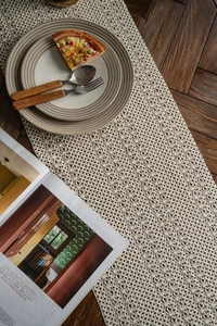Close-up of cream white crochet table runner with tassels on a dark wood background