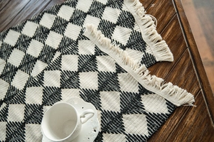 Detailed weave texture of black and white diamond pattern table runner with soft tassels